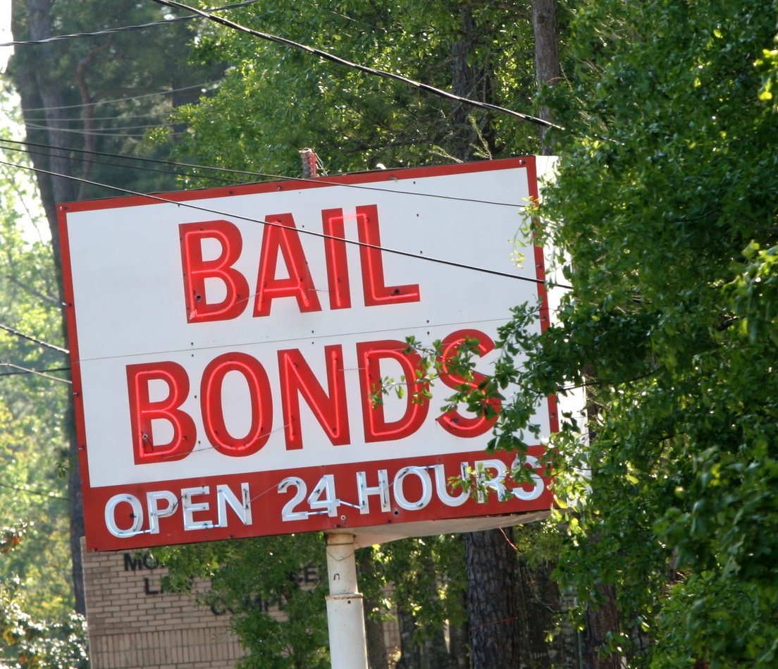 a red and white neon sign showing a Bail Bonds office that is open 24 hours a day