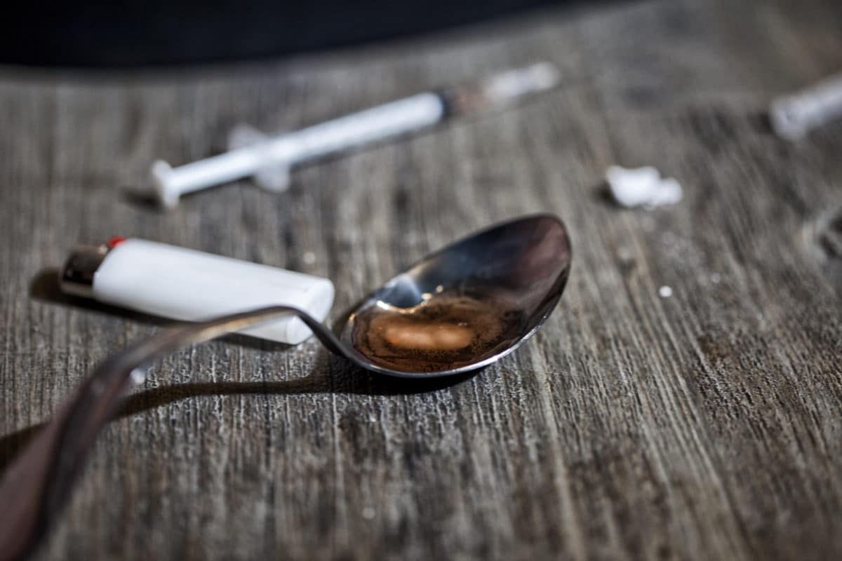 Close up of heroin and equipment comprised of a syringe, a lighter and a spoon