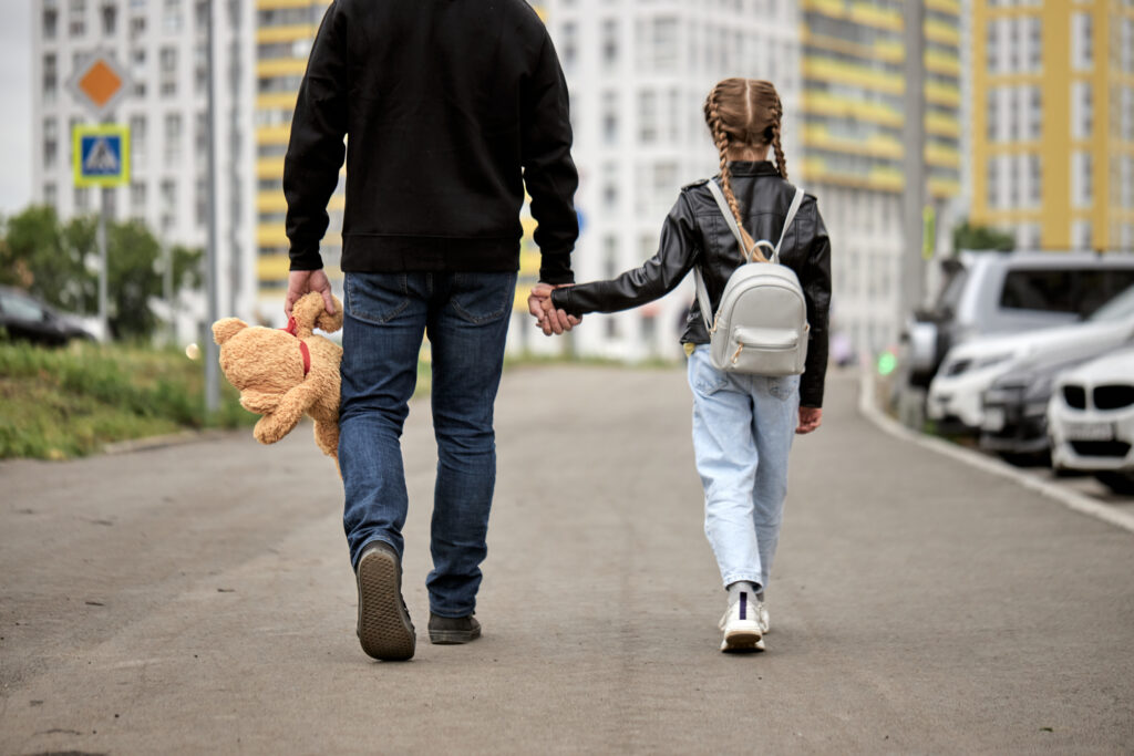 Pedophile man holds the hand of teenage girl in street. The concept of kidnapping